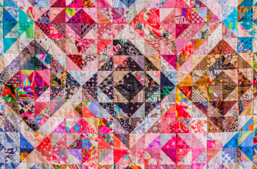 A colourful patchwork quilt made from many different patterned fabric pieces, forming heart shapes across the design.