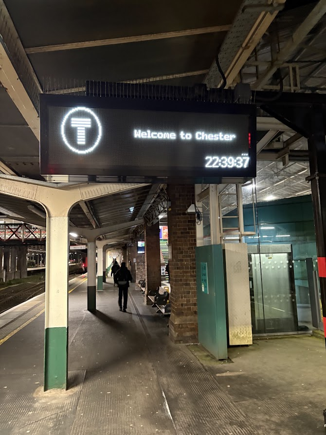 Chester railway station late at night, with a sign reading “Welcome to Chester” at 22:39, during a long journey home.